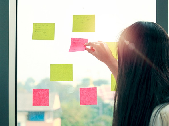 Researcher looks at post-it notes on window creativity innovation ideas_crop